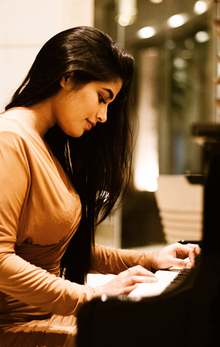 Female pianist performing on stage, UK entertainer visa application, Nexus Law Firm.