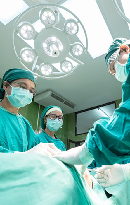 Senior doctor and two assistants performing surgery in clean, well-lit operating theater - highlighting expertise and patient care.